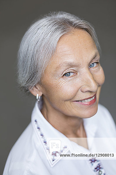 Portrait of smiling enior woman with grey hair and blue eyes