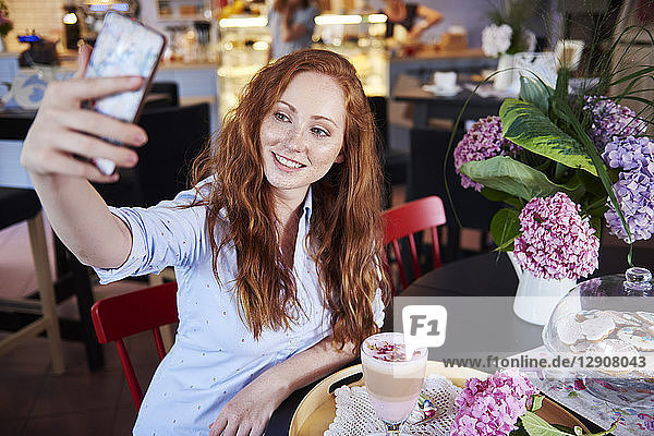 Smiling young woman taking a selfie in a cafe