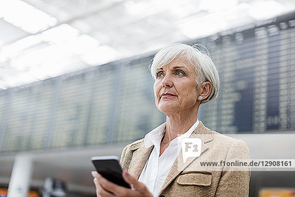Senior businesswoman holding cell phone at the airport