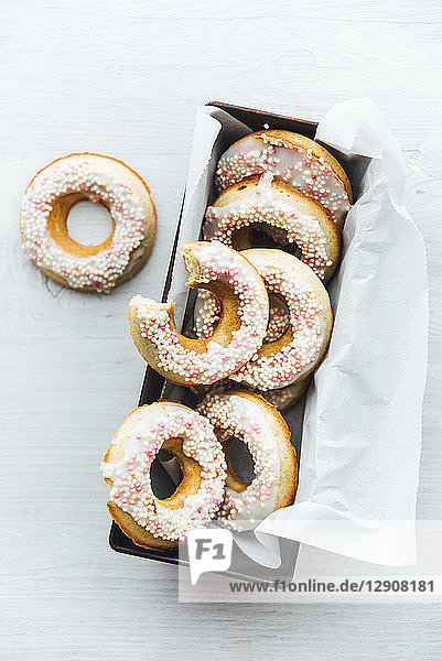 Cake pan of homemade doughnuts with icing and sugar beads