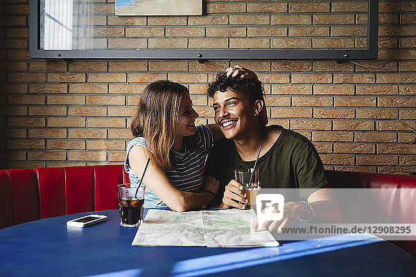 Happy young couple sitting at table in a cafe with map