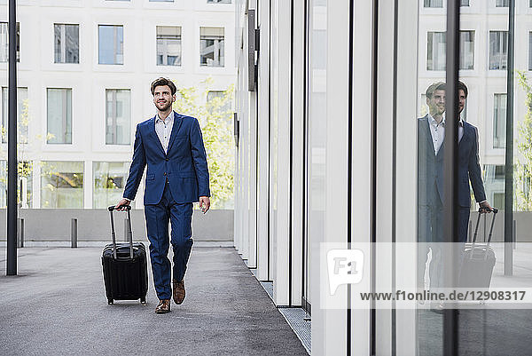 Smiling businessman with baggage in the city on the move