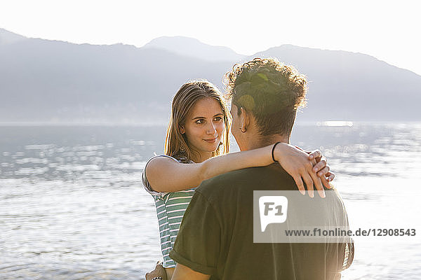 Affectionate young woman embracing boyfriend at the lakeside