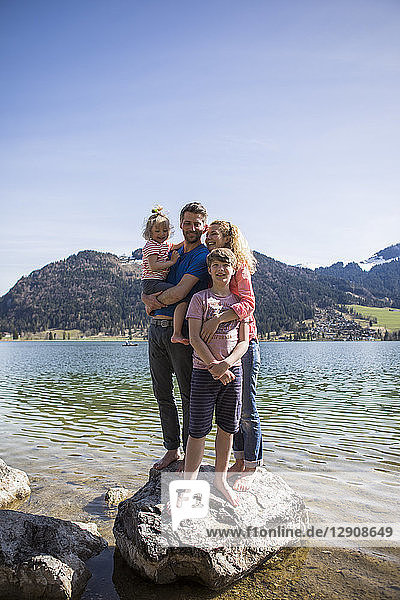 Austria  Tyrol  Walchsee  happy family standing on boulder in the lake