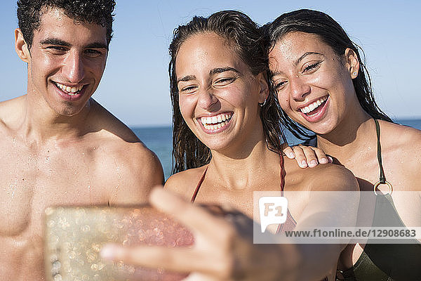Happy friends taking selfies on the beach