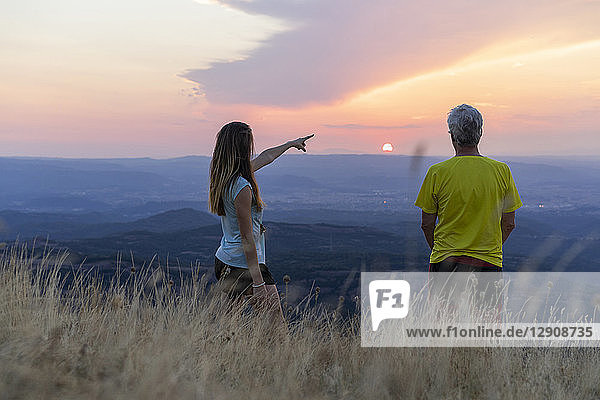 Spain  Catalonia  Montcau  senior father and adult daughter looking at view from top of hill during sunset