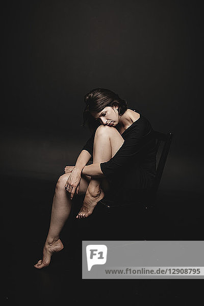 Portrait of woman wearing black sitting in front of black background