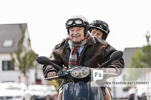 Happy senior couple riding motor scooter
