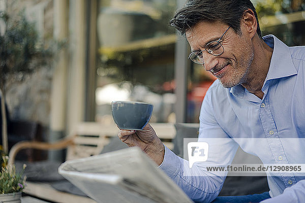 Mature businessman sitting in coffee shop  drinking coffee