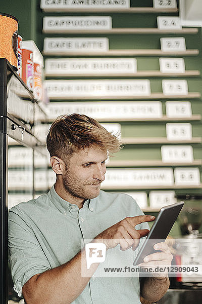 Young business owner using digital tablet in his coffee shop