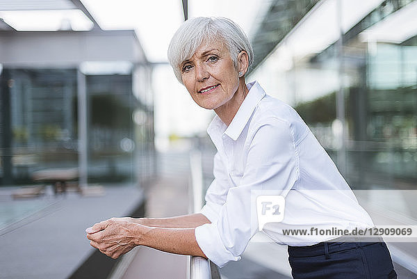 Portrait of confident senior woman leaning on railing in the city