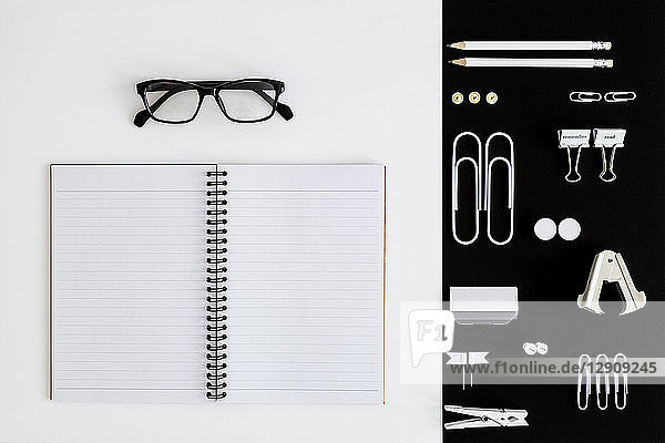 White office utensils on black background and notepad and glasses on whilte background