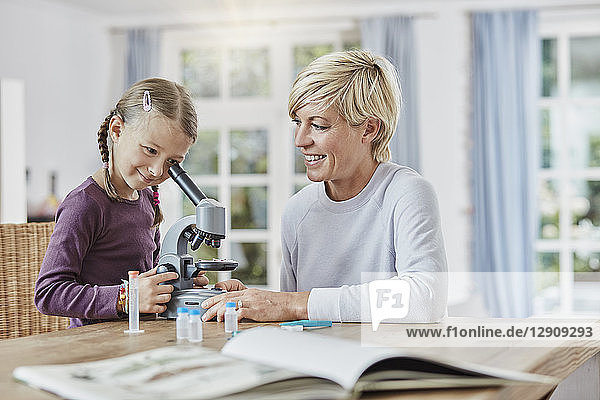 Mother and daughter using microscope at home