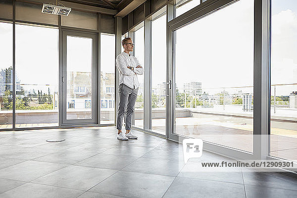 Businessman standing in empty room looking out of panorama window