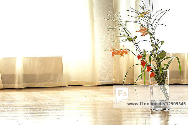 Bunch of flowers in a vase standing on wooden floor