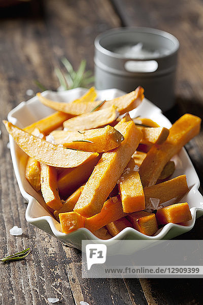 Sweet potato fries with rosmary and salt in porcelain bowl