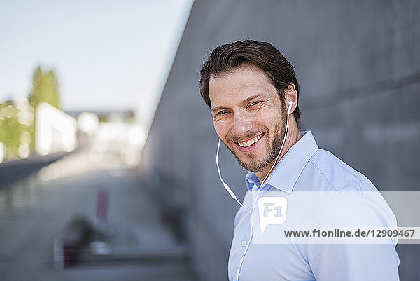 Portrait of smiling businessman wearing earbuds