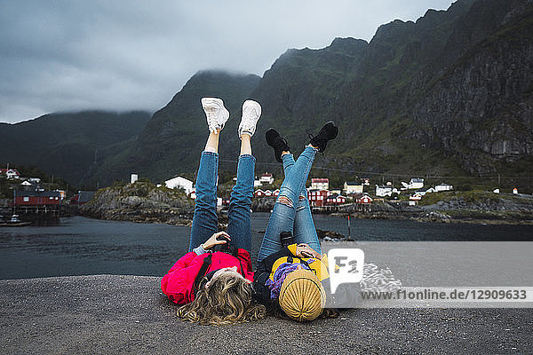 Norway  Lofoten  two young women lying on a pier at the coast