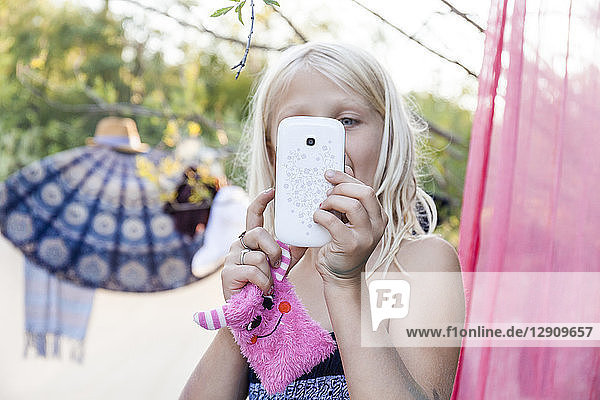 Girl holding cute sachet and using cell phone outdoors