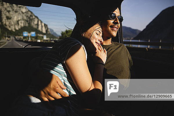 Smiling affectionate young couple sitting on backseat in a car