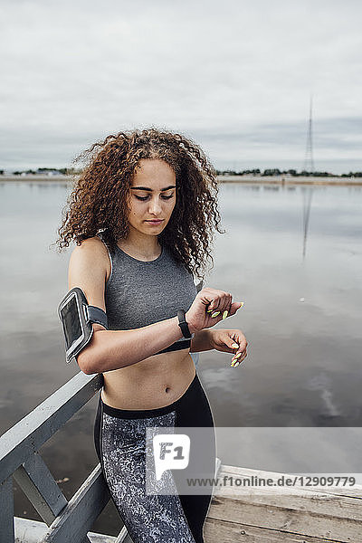 Young athletic woman at the riverside looking at wristwatch