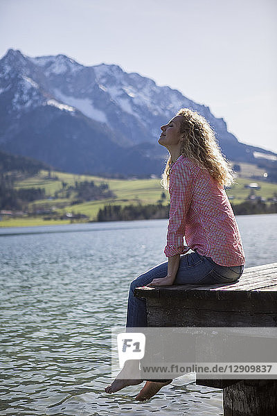 Austria  Tyrol  Walchsee  smiling woman sitting on a jetty at the lake