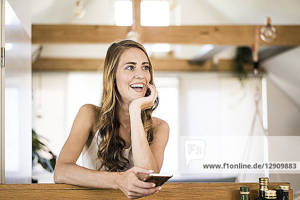 Happy brunette woman with cell phone at home