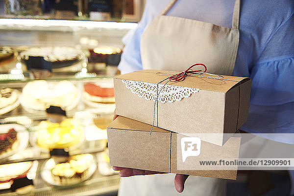 Close-up of woman holding cake boxes in a confectionery shop