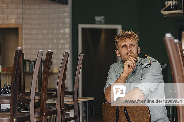 Young business owner sitting in his coffee shop  thinking