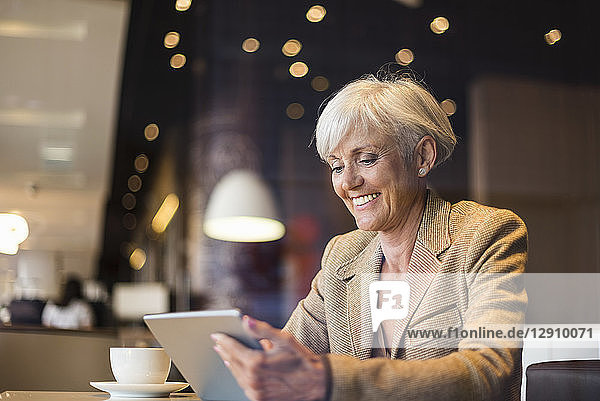 Smiling senior businesswoman using tablet in a cafe
