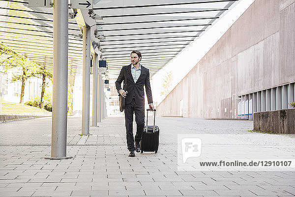 Businessman on the move pushing rolling suitcase