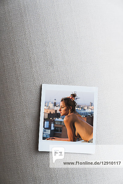 Instant photo of topless young woman on balcony
