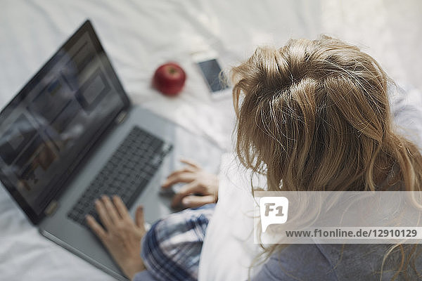 Woman sitting on bed  using laptop