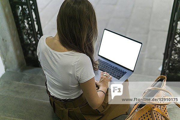 Woman sitting on a staircase using laptop