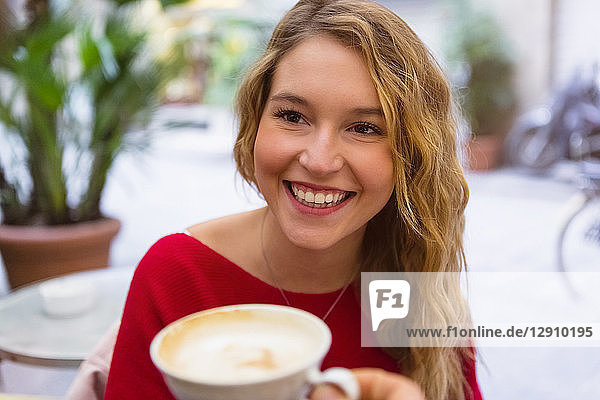 Portrait of laughing young woman with tea cup at pavement cafe