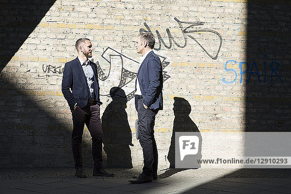 Two businessmen talking at graffiti wall