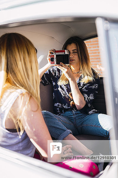 Photographer taking picture of young woman sitting in a car