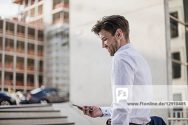 Businessman standing in the city using cell phone