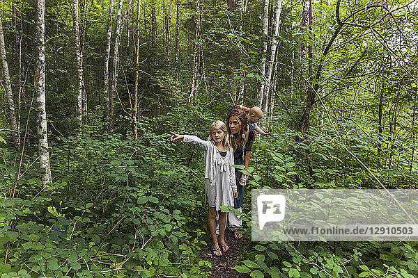 Girl hiking in the woods showing the way to mother and little brother