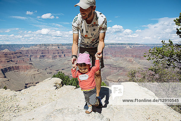 USA  Arizona  Grand Canyon National Park  father and baby girl on viewpoint  girl learning to walk