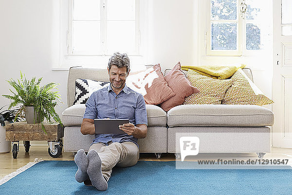 Man sitting in living room  using digital tablet