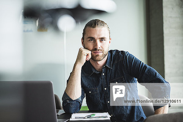 Portrait of confident casual businessman at desk in office
