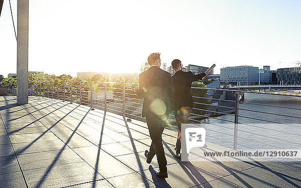 Two businessmen walking on a bridge in the city