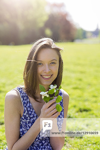 Portrait of smiling young woman in a park holding flowers