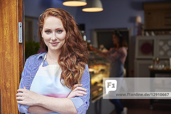 Portrait of smiling young woman at the entrance of a bakery