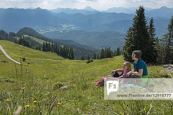 Germany  Bavaria  Brauneck near Lenggries  happy young couple having a break sitting in meadow in alpine landscape