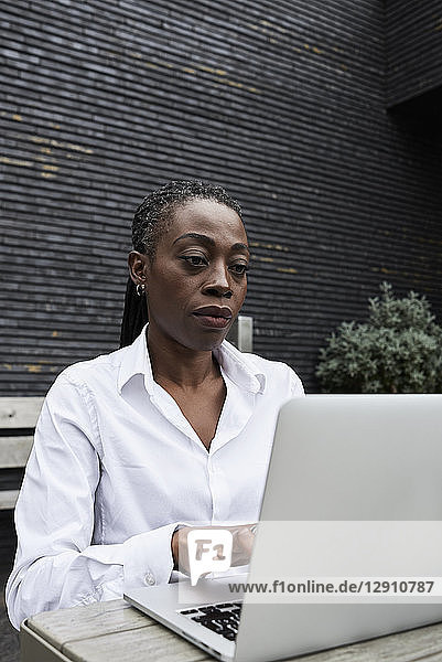 Portrait of businesswoman sitting on terrace of a coffee shop working on laptop