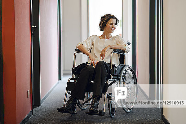 Disabled business woman sitting in wheelchair  with laptop on knees