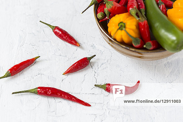 Five red chili pods and bowl of various chili peppers