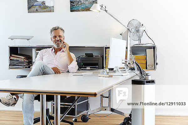 Portrait of smiling businessman sitting at desk in office